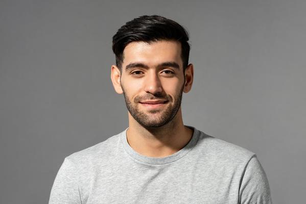 close-up-portrait-of-smiling-handsome-young-caucasian-man-face-looking-at-camera-on-isolated-light-gray-studio-background-photo